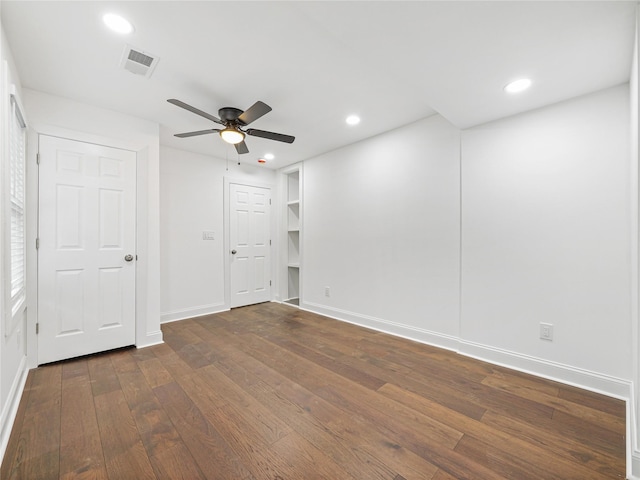 spare room with dark wood-type flooring, built in features, and ceiling fan