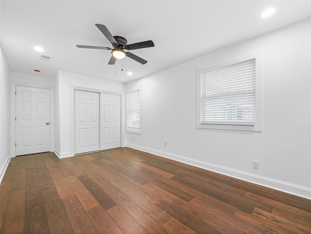 unfurnished bedroom with multiple windows, ceiling fan, dark hardwood / wood-style floors, and a closet