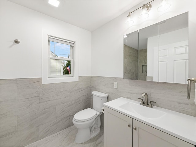 bathroom with vanity, tile walls, and toilet