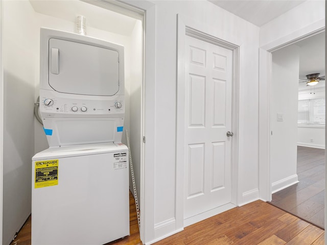 laundry area featuring stacked washer and dryer, hardwood / wood-style flooring, and ceiling fan