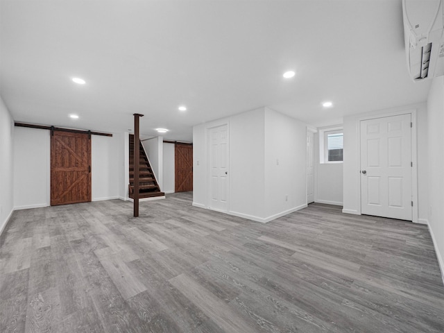 basement featuring a barn door and light hardwood / wood-style flooring