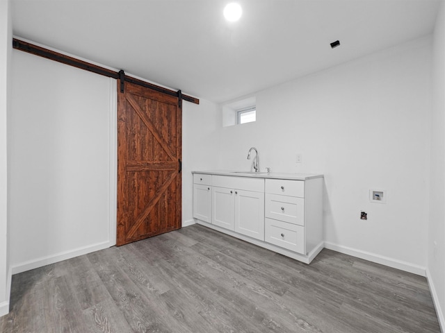 interior space featuring sink, cabinets, hookup for a washing machine, a barn door, and light hardwood / wood-style floors