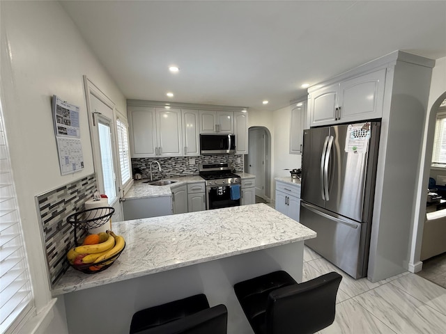 kitchen featuring a kitchen bar, sink, tasteful backsplash, appliances with stainless steel finishes, and kitchen peninsula