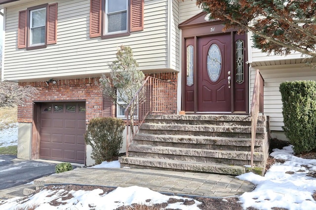 snow covered property entrance with a garage