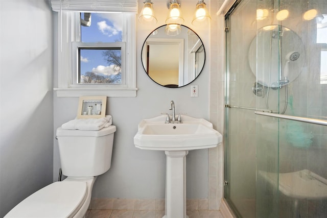 bathroom with a shower with shower door, tile patterned floors, toilet, and a healthy amount of sunlight