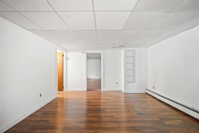 interior space with dark wood-type flooring, a baseboard radiator, built in features, and a paneled ceiling