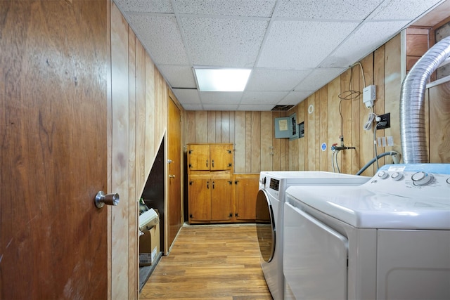 washroom with separate washer and dryer, wood walls, and light hardwood / wood-style flooring