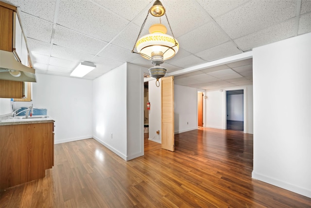 unfurnished living room with a drop ceiling, sink, and hardwood / wood-style flooring