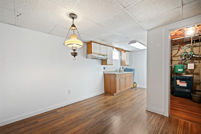 kitchen featuring hanging light fixtures, dark hardwood / wood-style floors, sink, and a drop ceiling