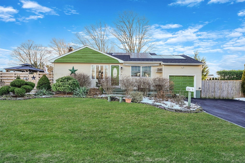 view of front of property with a garage, a front lawn, and solar panels