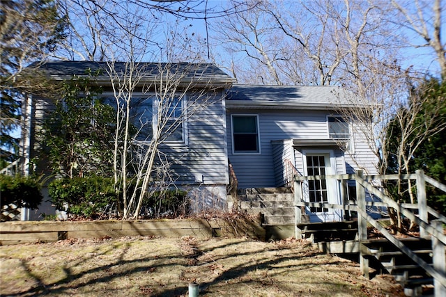 rear view of house featuring stairs and roof with shingles