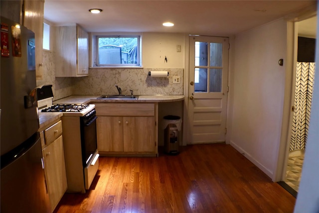 kitchen featuring range with gas stovetop, light wood-style flooring, freestanding refrigerator, a sink, and light countertops