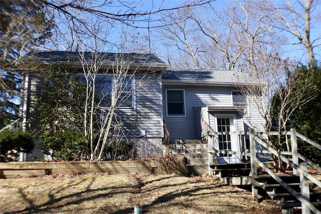 rear view of house with stairs and roof with shingles