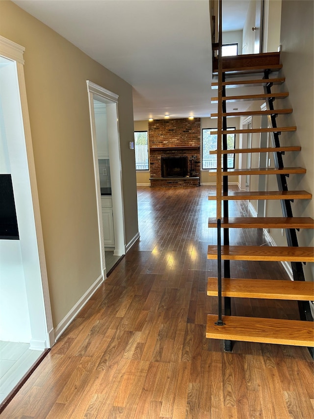 stairway with wood-type flooring and a fireplace