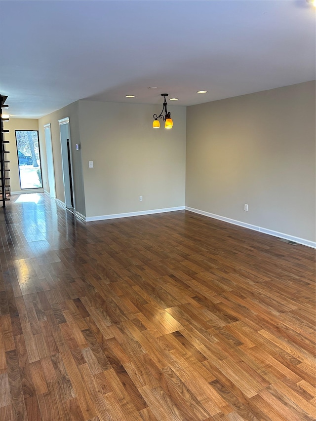 spare room with dark hardwood / wood-style floors and a chandelier