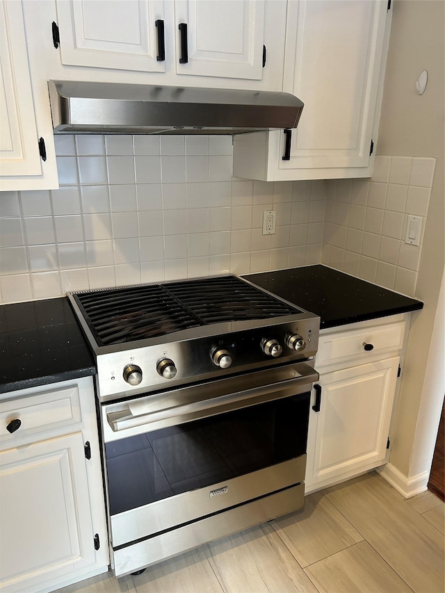 kitchen with wall chimney exhaust hood, light hardwood / wood-style flooring, stainless steel range with gas stovetop, white cabinets, and backsplash