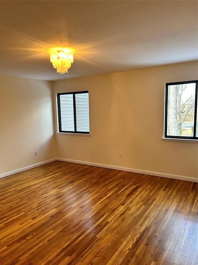 unfurnished room featuring dark wood-type flooring and a chandelier