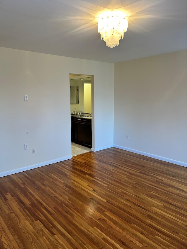 unfurnished room featuring dark wood-type flooring and a notable chandelier