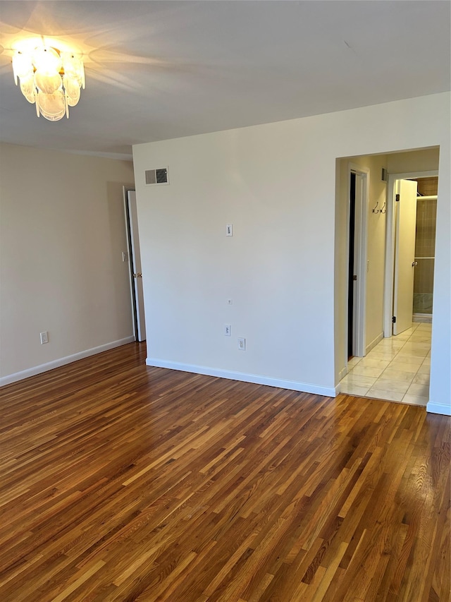 empty room with an inviting chandelier and light wood-type flooring