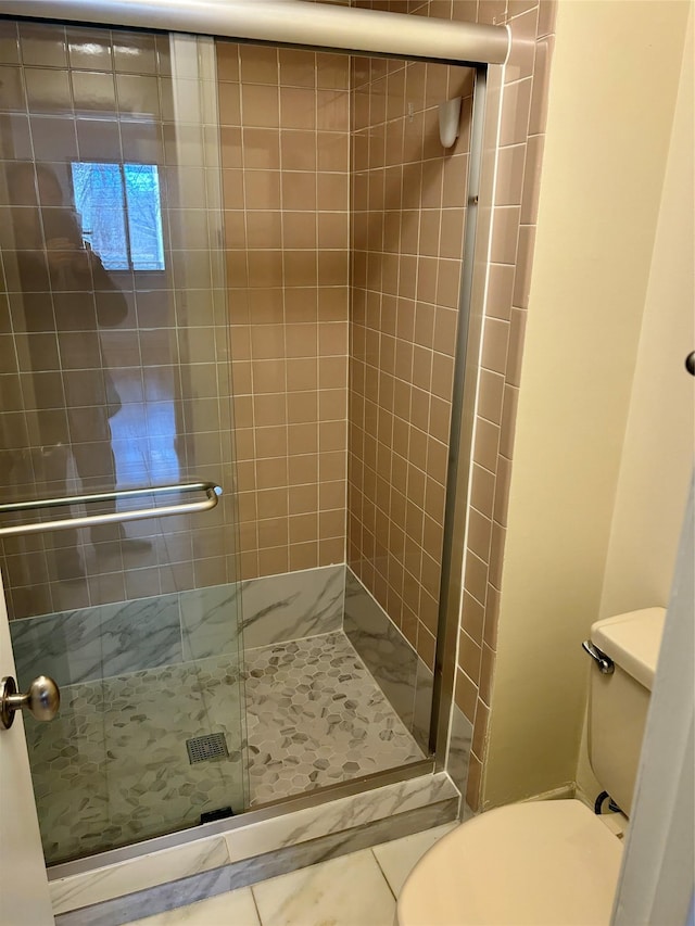 bathroom with tile patterned flooring, toilet, and a shower with shower door