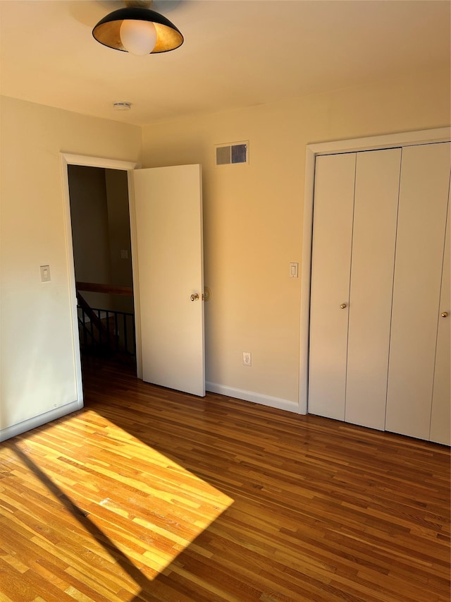 unfurnished bedroom with hardwood / wood-style flooring and a closet