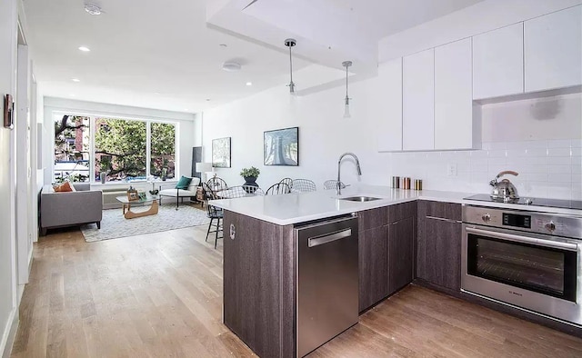 kitchen featuring sink, appliances with stainless steel finishes, white cabinetry, dark brown cabinetry, and kitchen peninsula