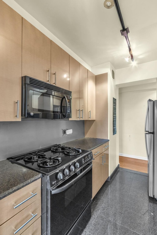 kitchen with dark stone countertops, light brown cabinetry, and black appliances