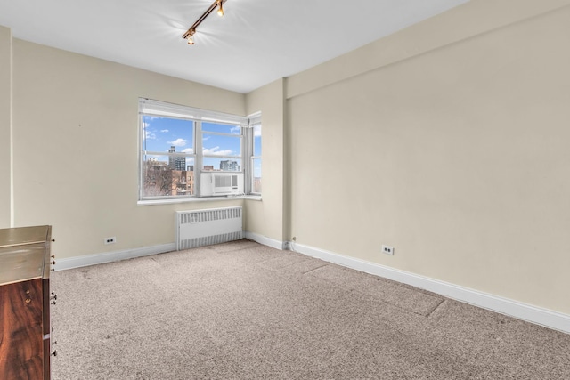 carpeted spare room featuring track lighting and radiator