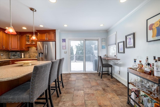 kitchen featuring a breakfast bar, pendant lighting, backsplash, ornamental molding, and stainless steel fridge with ice dispenser