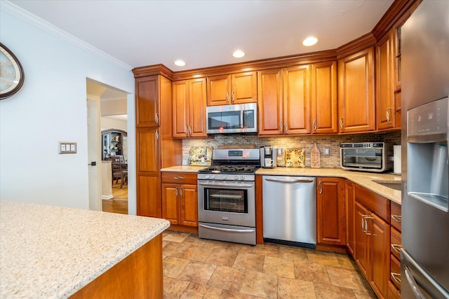 kitchen featuring tasteful backsplash, crown molding, light stone countertops, and appliances with stainless steel finishes