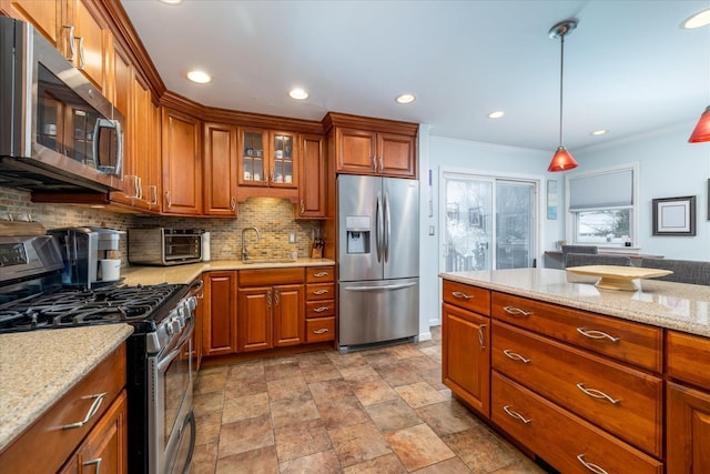 kitchen with appliances with stainless steel finishes, pendant lighting, tasteful backsplash, sink, and crown molding