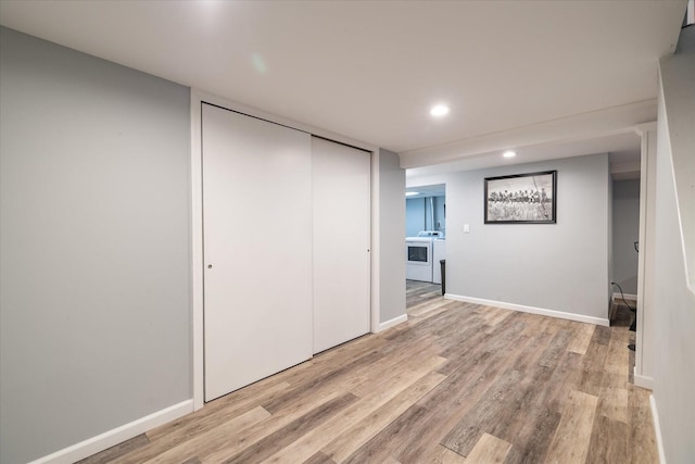 unfurnished bedroom with light hardwood / wood-style flooring, washing machine and dryer, and a closet