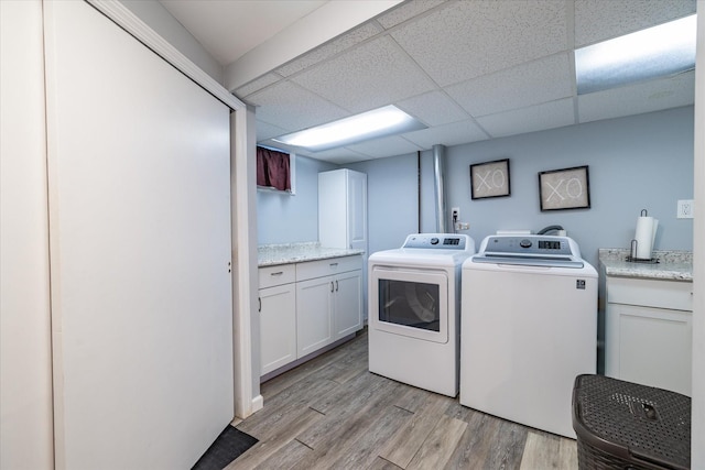 laundry area with separate washer and dryer, light hardwood / wood-style floors, and cabinets