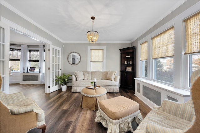 living room featuring an inviting chandelier, ornamental molding, a healthy amount of sunlight, and dark hardwood / wood-style flooring