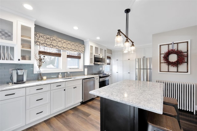 kitchen featuring white cabinetry, radiator, a center island, and appliances with stainless steel finishes