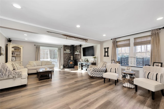 living room with wood-type flooring, ornamental molding, and a wood stove