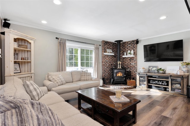 living room featuring hardwood / wood-style flooring, ornamental molding, and a wood stove