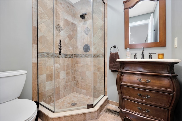 bathroom with vanity, toilet, a shower with shower door, and tile patterned flooring