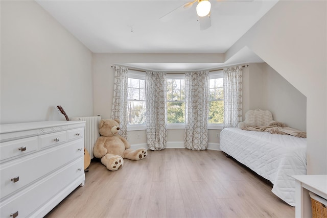 bedroom with radiator, light hardwood / wood-style flooring, and ceiling fan