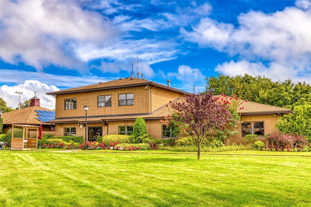 view of front of home with a front yard and solar panels