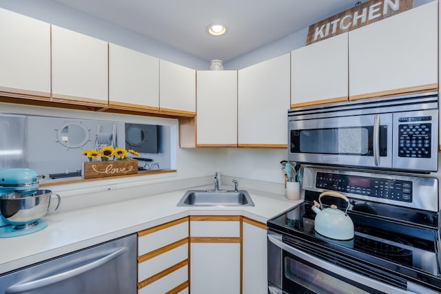 kitchen with stainless steel appliances, sink, and white cabinets