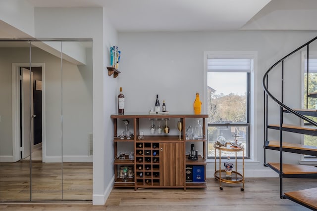 bar with hardwood / wood-style flooring and a healthy amount of sunlight