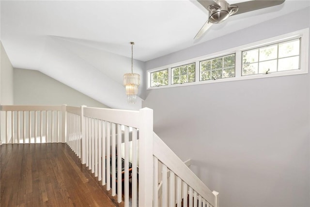 hall featuring a notable chandelier, dark wood-type flooring, and vaulted ceiling