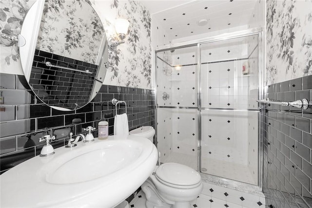 bathroom with walk in shower, sink, tile walls, and toilet