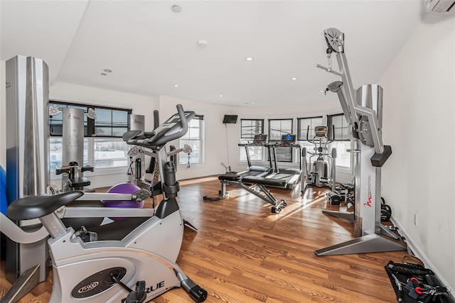 gym with wood-type flooring and a wall mounted air conditioner