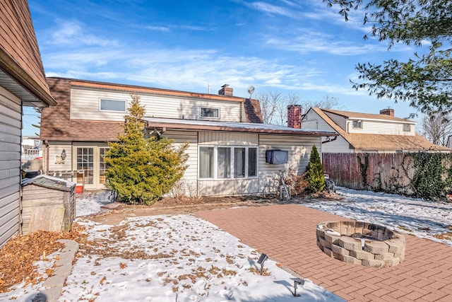 snow covered property with an outdoor fire pit and a patio area