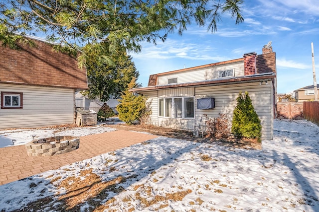 snow covered rear of property featuring a fire pit and a patio area