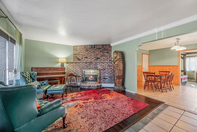 tiled living room with a fireplace, ornamental molding, and wood walls