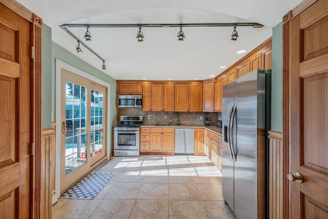 kitchen with tasteful backsplash, appliances with stainless steel finishes, sink, and light tile patterned floors