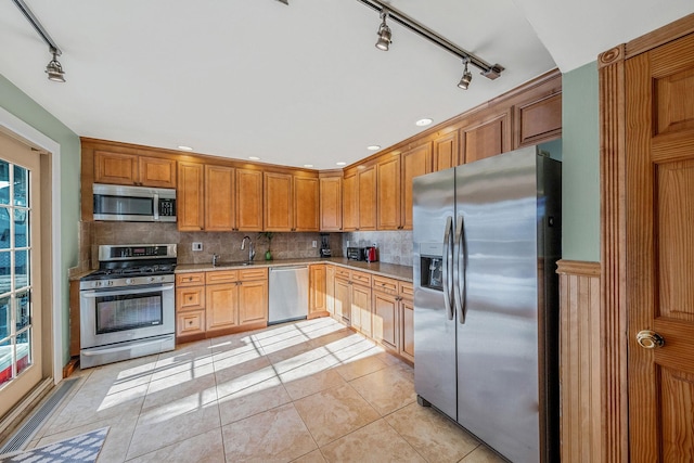 kitchen with light tile patterned floors, decorative backsplash, stainless steel appliances, and sink